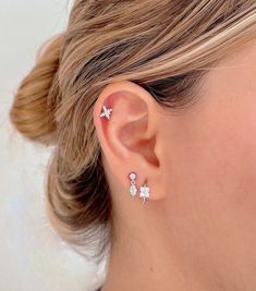 a close up of a woman's ear with two small white flowers on it