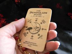 the pendulum board is in someone's hand with a key chain attached to it