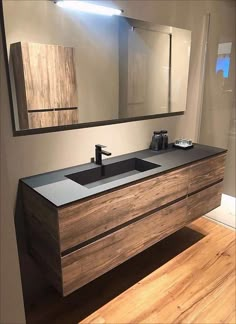 a bathroom vanity with two sinks and large mirror over it's top, in front of a wooden floor