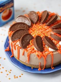 a cake with orange icing and chocolate cookies on top is sitting on a blue plate