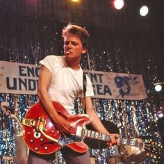 a young man playing an electric guitar on stage