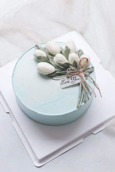 there is a cake that has flowers on the top and a tag with love you written on it