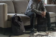 a man sitting on a couch with his luggage in front of him and a backpack behind him