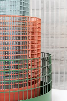 two orange and green vases sitting next to each other on top of a table