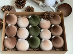 a box filled with lots of different colored balls next to pine cones and other decorations