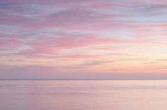 the sky is pink and purple as it reflects in the water