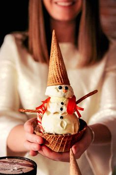 a woman holding an ice cream cone with a snowman on top