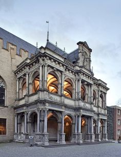 an old building with columns and arches on the front is lit up by lights at night