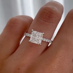 a woman's hand with a diamond ring on top of her finger and an engagement band