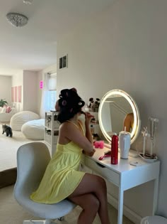 a woman sitting in front of a mirror on top of a desk next to a bed