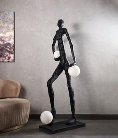 a black and white statue with three balls in it's body next to a chair