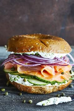 a sandwich with meat, cheese and onions on it sitting on a table next to a knife