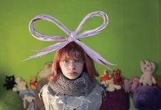 a woman with glasses and a scarf on her head is standing in front of stuffed animals