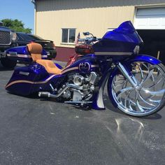 a blue motorcycle parked in a parking lot next to a building and another vehicle behind it