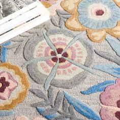 a close up of a rug with flowers on it and a magazine laying next to it