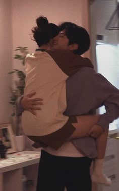 two people hugging each other in a room