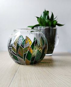 a potted plant sitting on top of a wooden table next to a glass vase