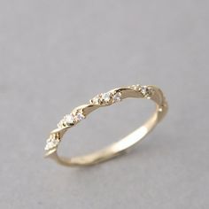 a gold wedding ring with three diamonds on it's side, sitting on a gray surface