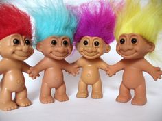 three troll dolls with different colored hair standing next to each other