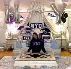 a woman sitting on top of a white bed in a room filled with balloons and furniture