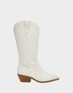 a pair of white cowboy boots with studdings on the side and wooden heel