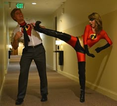 a man and woman dressed up as batman and catwoman standing in an office hallway