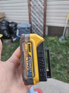 a hand holding a yellow and black power tool