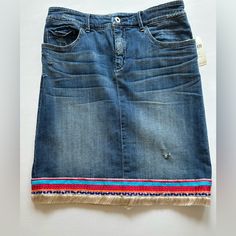 a denim skirt with colorful stripes and fringes on the bottom is displayed in front of a white background