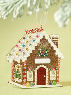 a gingerbread house ornament hanging from a christmas tree