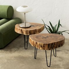 two wooden tables sitting next to each other on top of a cement floor near a green couch