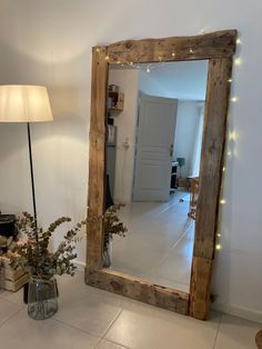 a mirror sitting on top of a white floor next to a lamp