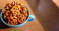 a blue bowl filled with pretzels sitting on top of a wooden table