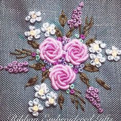 a close up of a flower on a piece of cloth with beads and flowers in the center