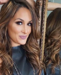 a woman is getting her hair done in front of a mirror and looking into the camera