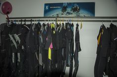 a bunch of wetsuits are hanging on a rack