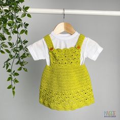 a green crocheted dress hanging on a clothesline next to a potted plant