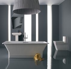 a white bath tub sitting in a bathroom next to a toilet and a lamp hanging from the ceiling