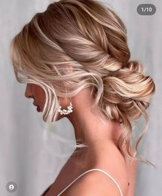 a woman with blonde hair in a low updo and earrings on her head is looking back