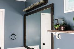 a bathroom with blue walls, white trim and a mirror on the wall above it