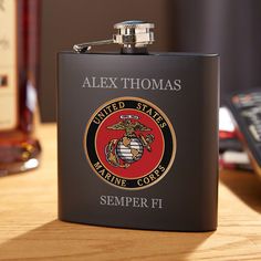 a black flask with the emblem of an armed marine corp on it sitting on a table