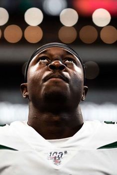 a close up of a person wearing a football uniform with lights in the back ground