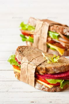 two sandwiches with meat, lettuce and tomato on white wooden background - stock photo - images