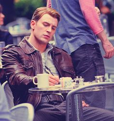 a young man sitting at an outdoor table with his eyes closed