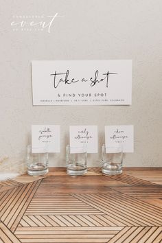 three shot glasses sitting on top of a wooden table next to a sign that says take a shot and find your spot