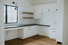 an empty kitchen with white cabinets and black counter tops, along with wood flooring