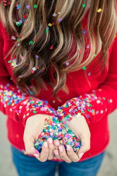 a girl in red shirt holding out her hands with sprinkles on it