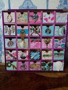 a purple and pink display case filled with lots of different items on top of a wooden table