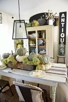 a white table topped with lots of pumpkins and greenery on top of it