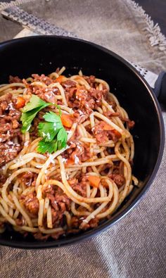 a bowl filled with spaghetti and meat on top of a table