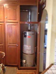 an open cabinet with a water heater in the middle and cabinets behind it,